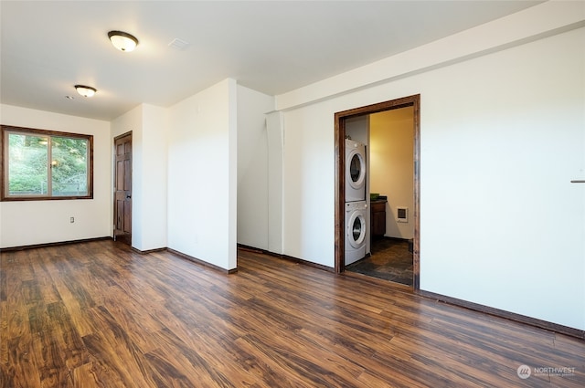 spare room featuring stacked washing maching and dryer and dark hardwood / wood-style flooring