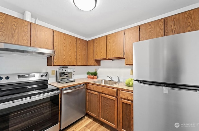 kitchen featuring stainless steel appliances, sink, and light wood-type flooring