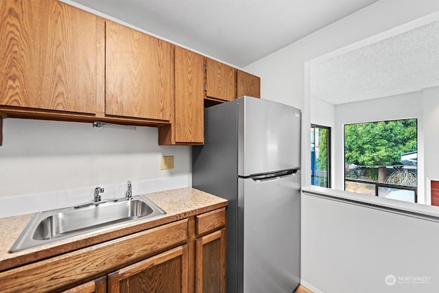 kitchen with stainless steel refrigerator, sink, and a textured ceiling