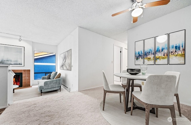 dining room featuring a baseboard heating unit, ceiling fan, carpet floors, and a textured ceiling