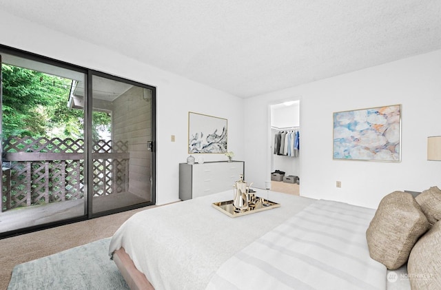 carpeted bedroom featuring a walk in closet, access to outside, and a textured ceiling