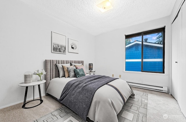 carpeted bedroom featuring baseboard heating and a textured ceiling