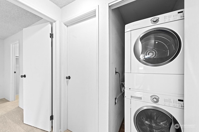 laundry area with stacked washer and clothes dryer, carpet, and a textured ceiling