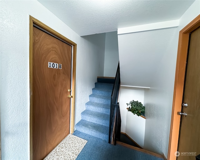 stairs with a textured ceiling and carpet