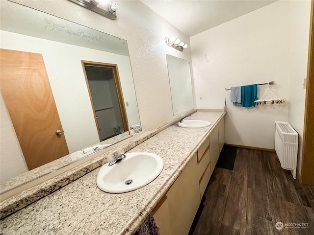 bathroom featuring toilet, vanity, radiator heating unit, and hardwood / wood-style floors