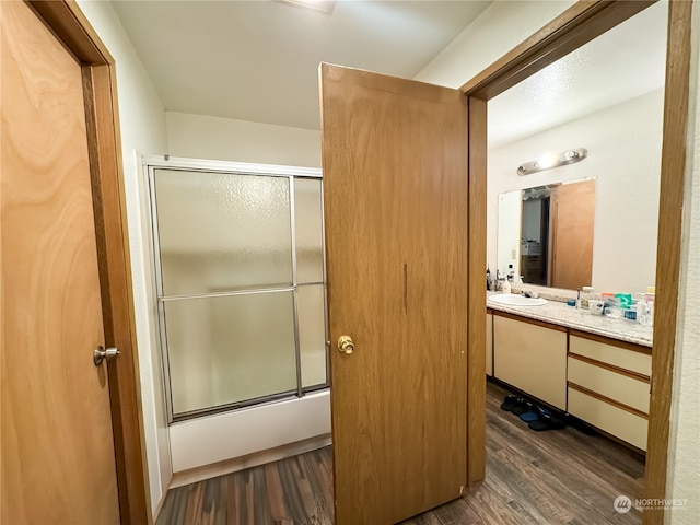 bathroom with wood-type flooring, vanity, and enclosed tub / shower combo