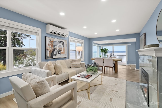 living room with a wall unit AC, a water view, and light hardwood / wood-style floors