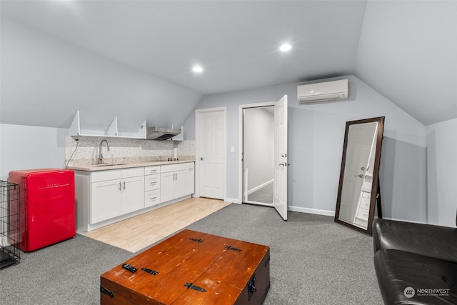 living room featuring light wood-type flooring, a wall unit AC, sink, and lofted ceiling