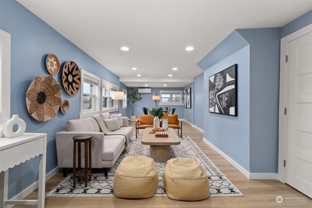 living room with an AC wall unit and light hardwood / wood-style flooring