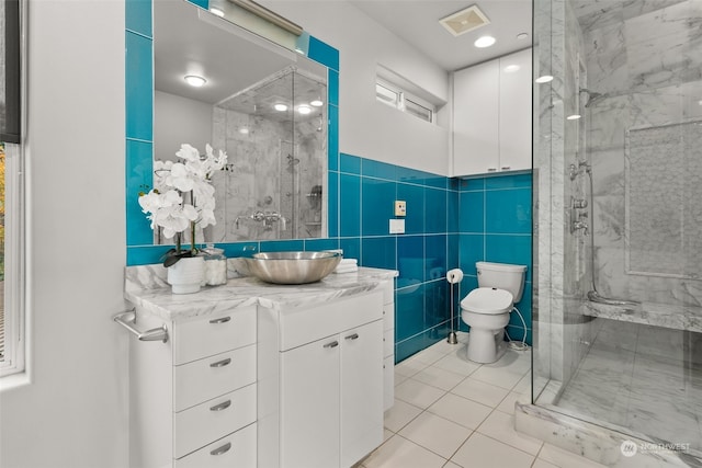 bathroom featuring a shower with shower door, vanity, toilet, and tile walls