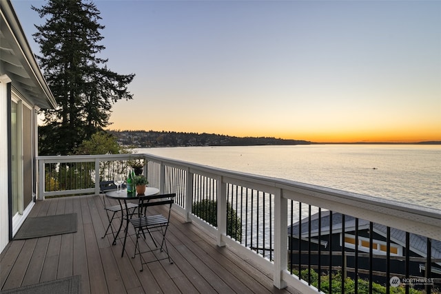 deck at dusk featuring a water view