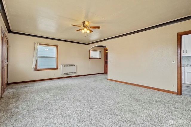 carpeted spare room featuring crown molding, heating unit, and ceiling fan