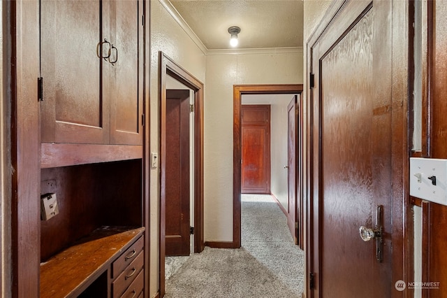 corridor with ornamental molding, light carpet, and a textured ceiling