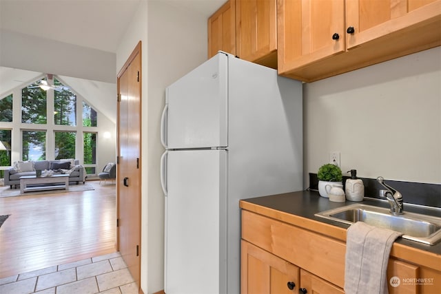 kitchen featuring sink, light wood-type flooring, ceiling fan, lofted ceiling, and white refrigerator