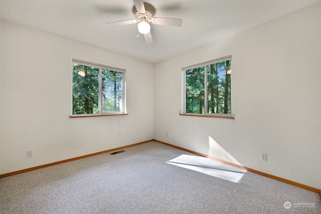 carpeted empty room with ceiling fan and plenty of natural light