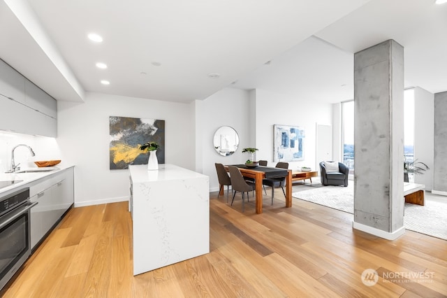 kitchen featuring sink, stainless steel oven, and light hardwood / wood-style floors