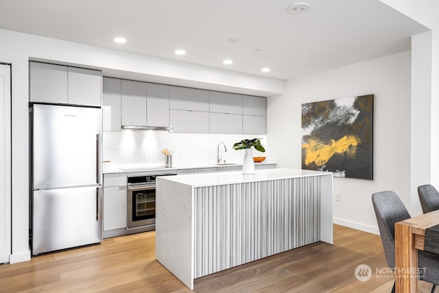 kitchen with sink, light hardwood / wood-style floors, stainless steel appliances, and a center island