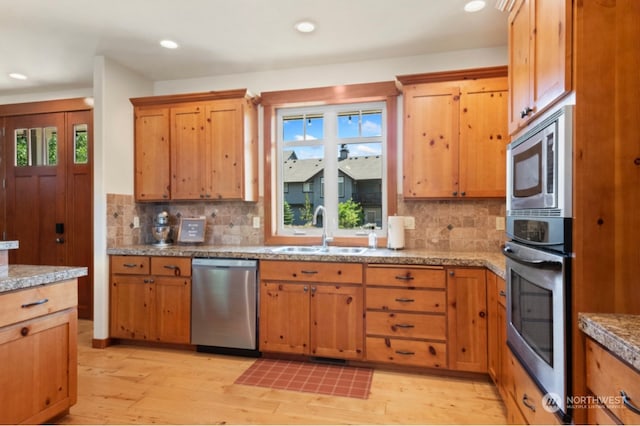 kitchen with a sink, stainless steel appliances, plenty of natural light, and light wood-style floors