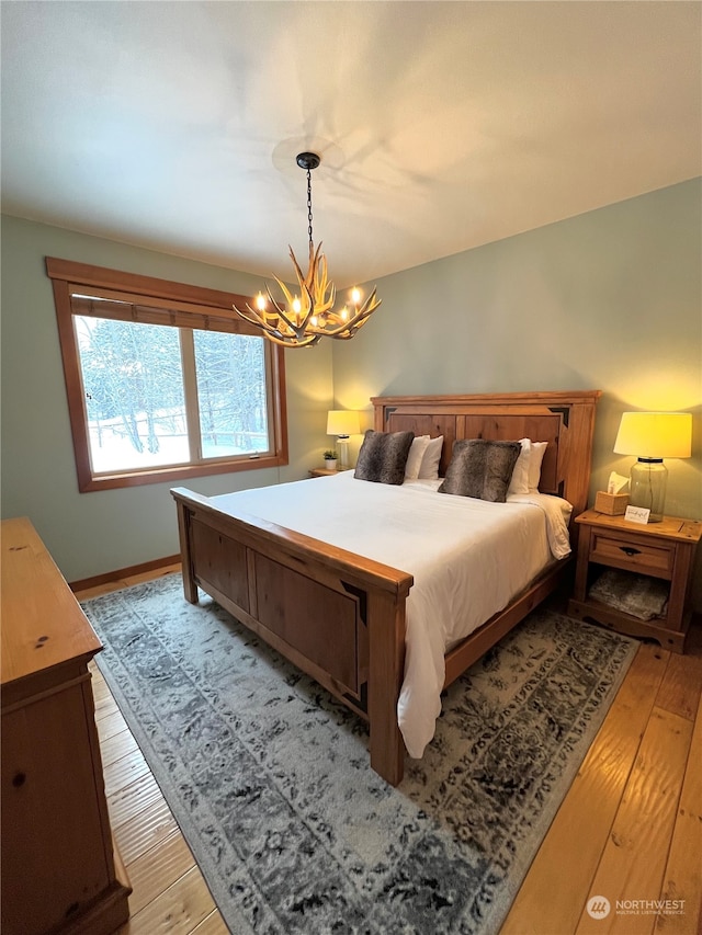 bedroom featuring baseboards, light wood finished floors, and a chandelier