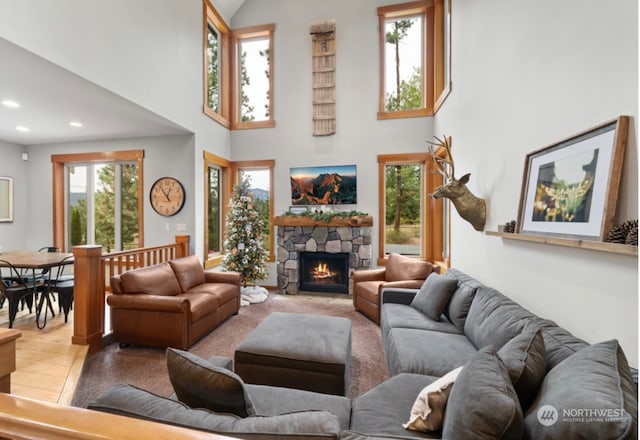 living room featuring a stone fireplace, recessed lighting, and a towering ceiling