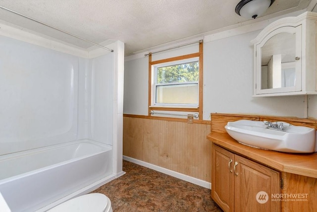 full bathroom with wooden walls, vanity, a textured ceiling, shower / washtub combination, and toilet