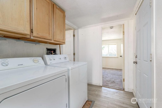 clothes washing area featuring baseboards, ornamental molding, cabinet space, light wood finished floors, and washing machine and clothes dryer