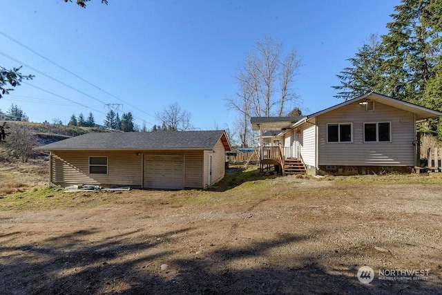 back of property with a garage, crawl space, driveway, and an outdoor structure