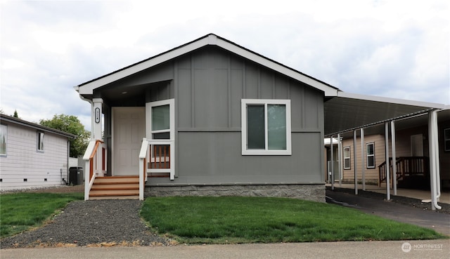 manufactured / mobile home featuring a front lawn, central air condition unit, and a carport