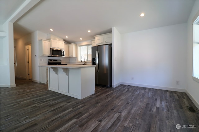 kitchen with dark wood-type flooring, sink, a center island, white cabinets, and appliances with stainless steel finishes