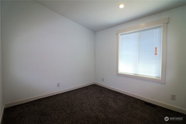 unfurnished room featuring dark carpet