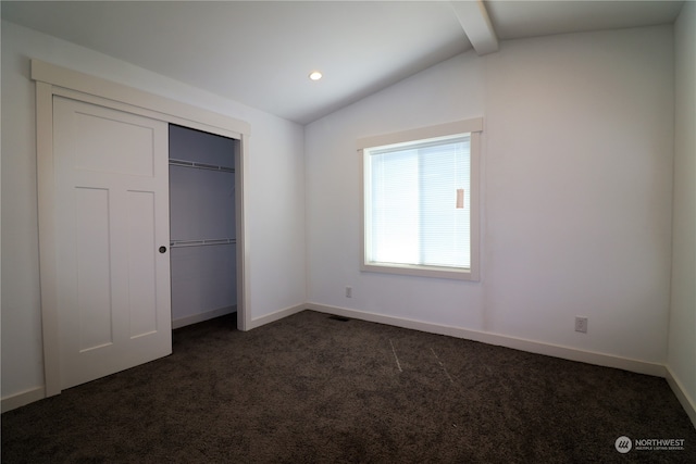 unfurnished bedroom with vaulted ceiling with beams, a closet, and dark carpet