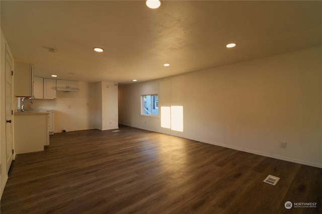 unfurnished living room featuring sink and dark wood-type flooring