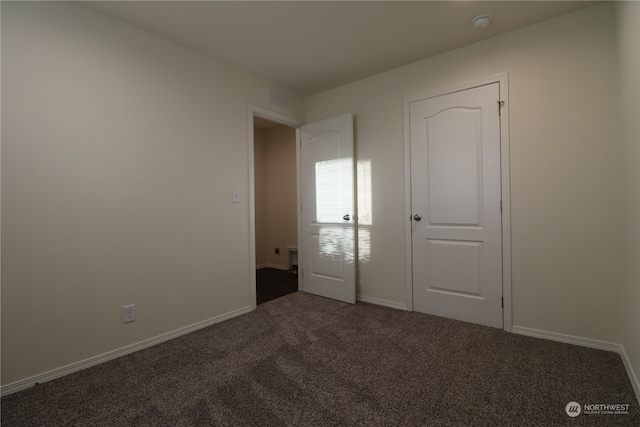 unfurnished bedroom featuring a closet and dark colored carpet