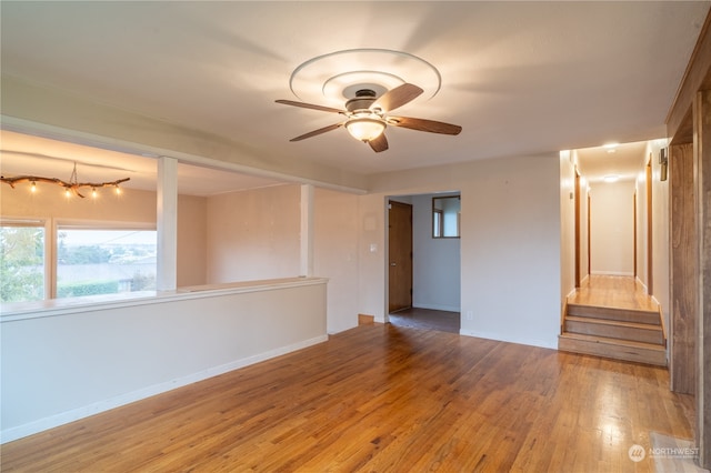 spare room with hardwood / wood-style floors and ceiling fan with notable chandelier