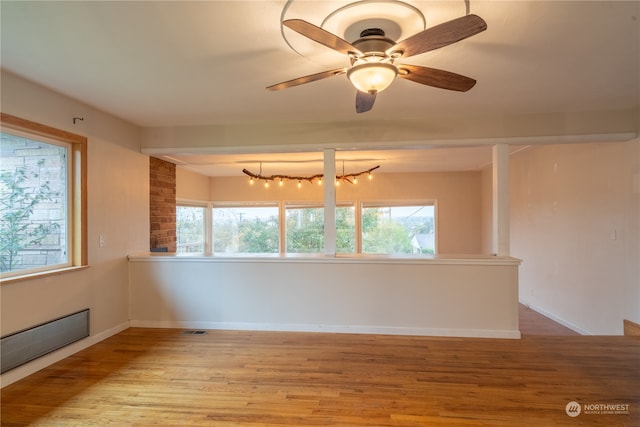 unfurnished room with ceiling fan with notable chandelier and light hardwood / wood-style flooring