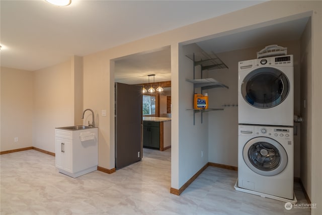 laundry room with stacked washing maching and dryer, sink, and a notable chandelier