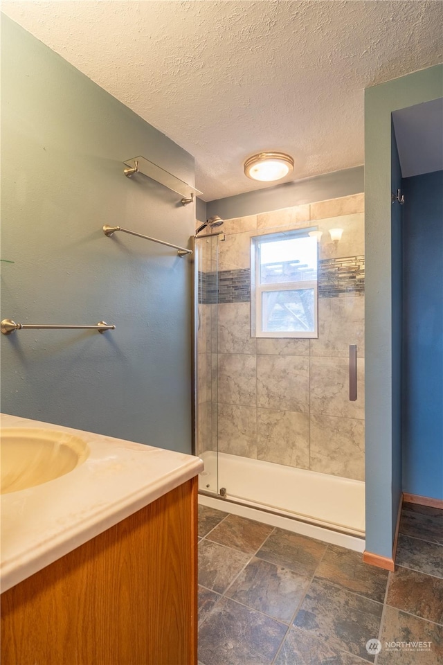 835 S Kiefer Dr, Moses Lake, WA 98837 - bathroom featuring vanity, baseboards, a stall shower, stone finish floors, and a textured ceiling