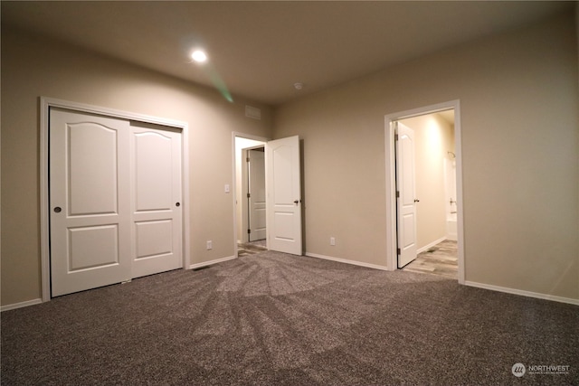 unfurnished bedroom with a closet, connected bathroom, and carpet flooring