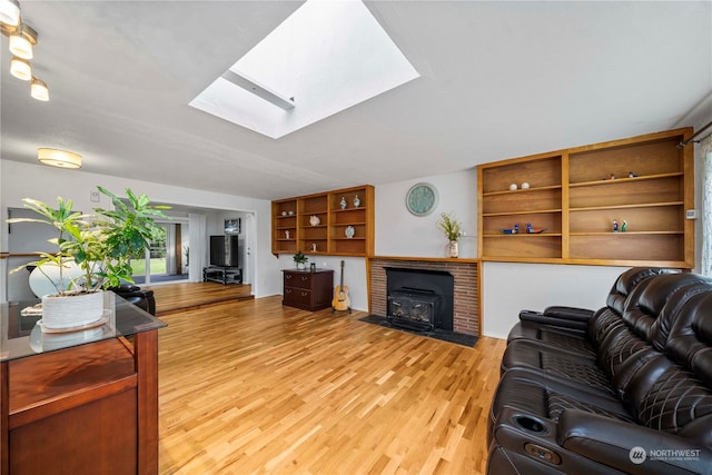 living room with light hardwood / wood-style floors, a wood stove, and a skylight