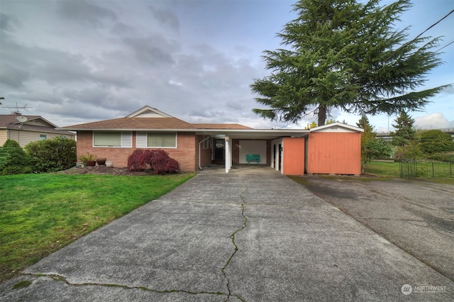 ranch-style home featuring a front yard, a carport, and a storage shed