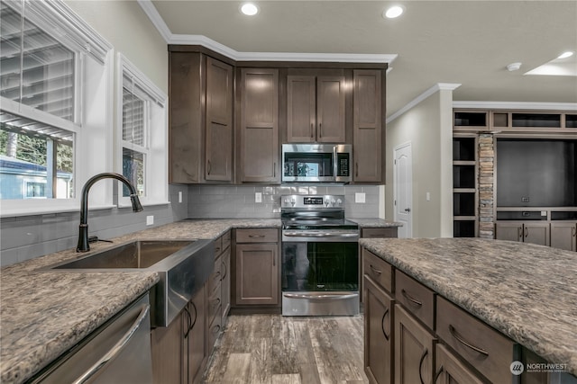 kitchen with appliances with stainless steel finishes, ornamental molding, sink, and dark wood-type flooring