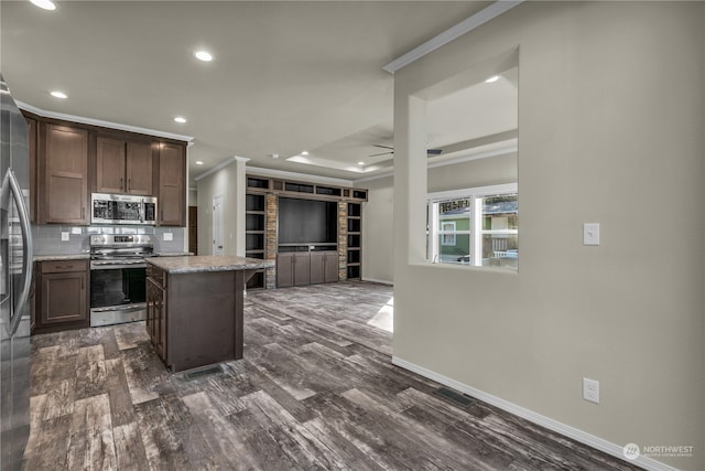 kitchen with tasteful backsplash, ceiling fan, a kitchen island, dark wood-type flooring, and stainless steel appliances