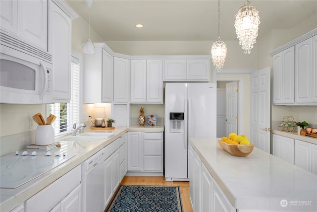 kitchen with hanging light fixtures, white cabinetry, a notable chandelier, sink, and white appliances