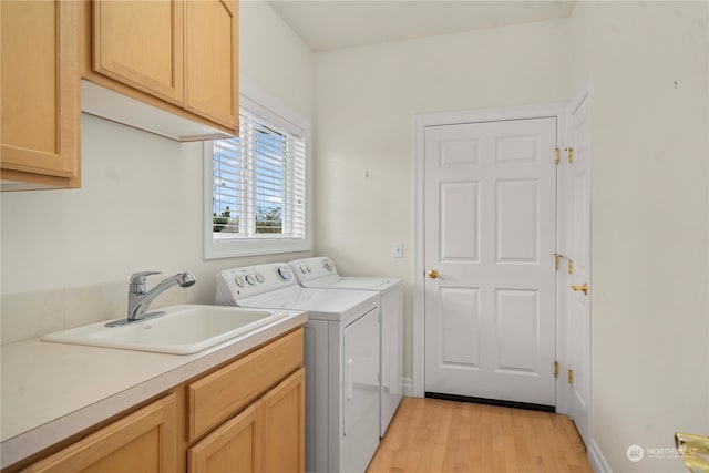 washroom with independent washer and dryer, cabinets, sink, and light wood-type flooring