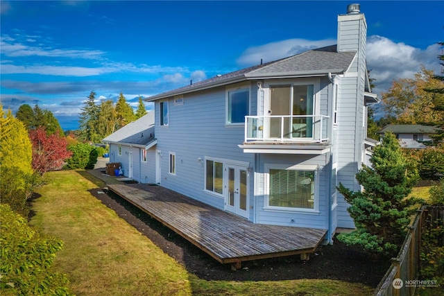 rear view of property with a balcony, a wooden deck, and a yard