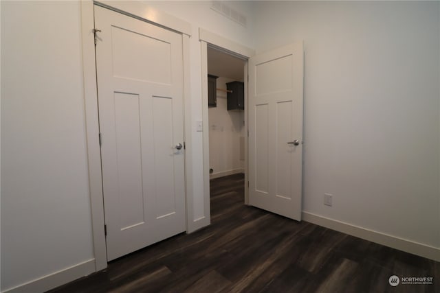 unfurnished bedroom with dark wood-type flooring and a closet