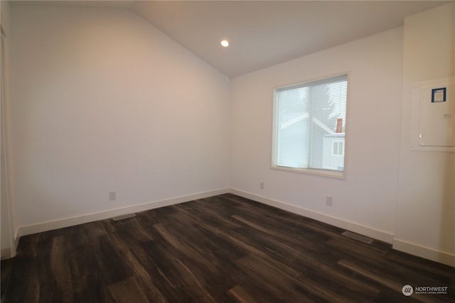 empty room featuring electric panel, vaulted ceiling, and dark hardwood / wood-style floors