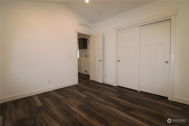 unfurnished bedroom with vaulted ceiling, a closet, and dark hardwood / wood-style flooring