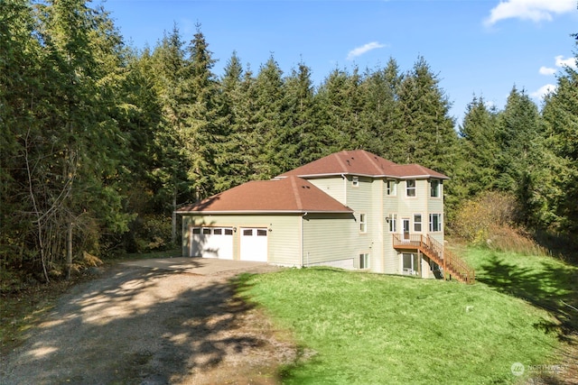 view of home's exterior with dirt driveway, a forest view, an attached garage, stairs, and a yard