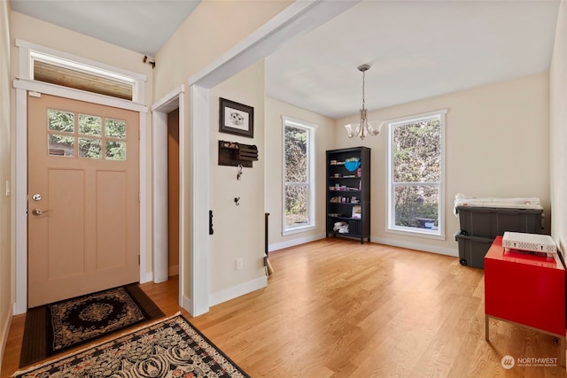 entrance foyer featuring a notable chandelier, baseboards, and light wood-style floors